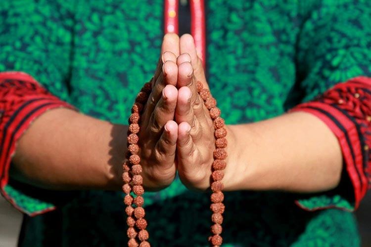 mains en namaste avec un mala en rudraksha