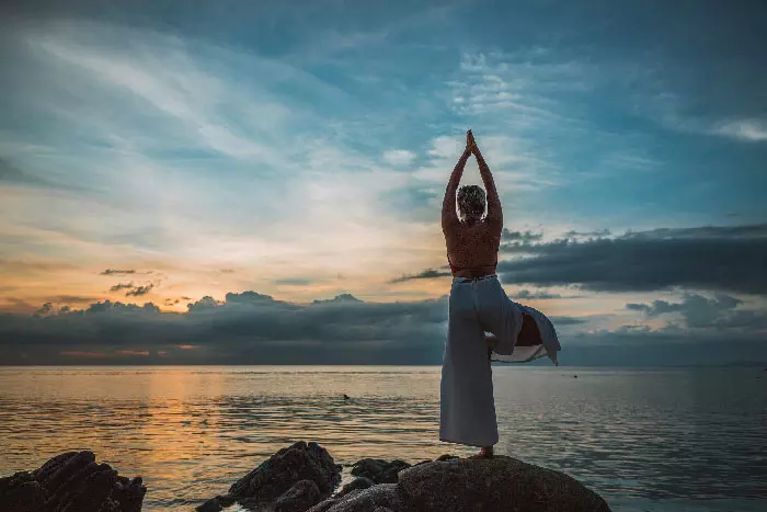 posture de yoga devant l'ocean au coucher du soleil